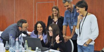 group of people gathered around a laptop and smiling